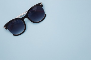 Women's sunglasses are on a blue background in the upper left corner. Horizontal paper texture.