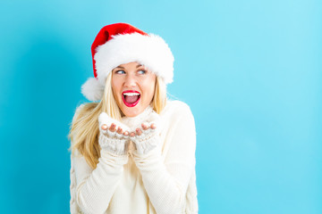 Happy young woman with Santa hat blowing a kiss