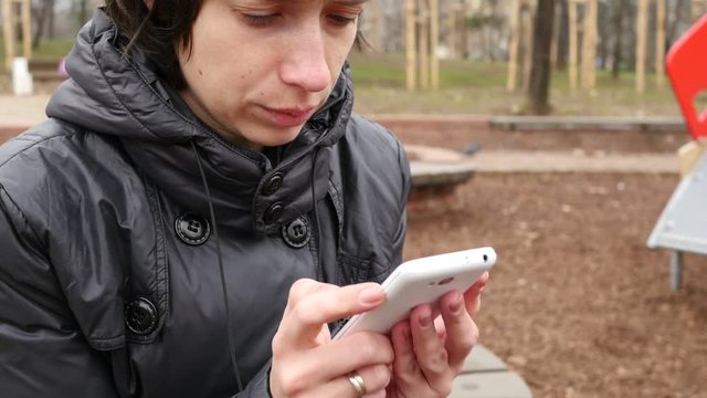 Female type slide her smartphone touchscreen outdoors in park