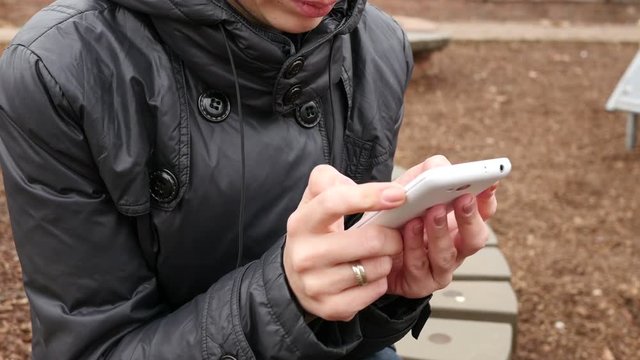 Female type slide her smartphone touchscreen outdoors in park