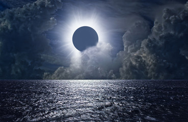 Total solar eclipse above the clouds and sea - obrazy, fototapety, plakaty