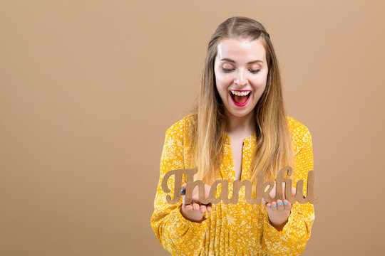 Young Woman Holding A Thankful Block On A Brown Background