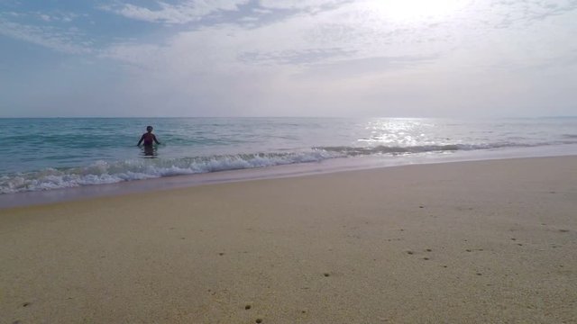A woman bathes in the calm ocean water on the beach. Portugal