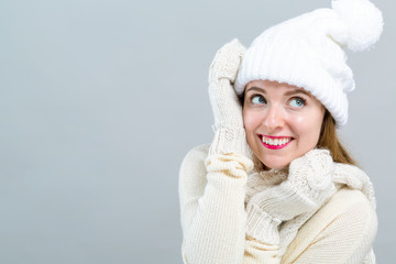 Young woman in a cold weather winter outfit on a gray background