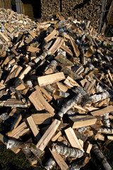 Pile and wall of cut birch wood and stacked wood logs ready for winter, standing on the grass