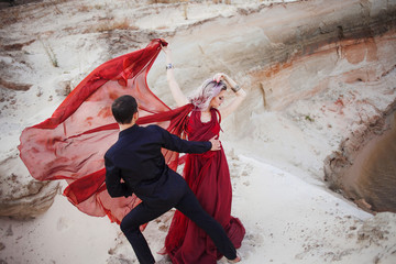 Love and passion, concept. Beautiful young couple dancing in desert. The man in black and woman in...