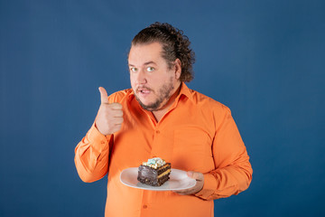 Funny fat man in orange shirt with a piece of chocolate cake on a plate