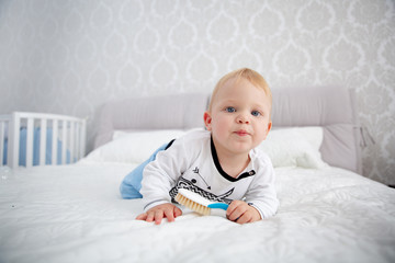 Fototapeta premium Playful little boy wearing blue pyjamas in bed