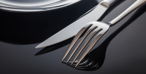 Empty plate with knife and fork on a black background