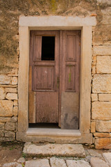 Fototapeta premium An old wooden door in a derelict sstone building in the Croatian hill village of Bale, also called Valle 