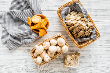 Collect mushroom concept. Champignons, oysters, chanterelles in basket near knife on grey background top view copy space