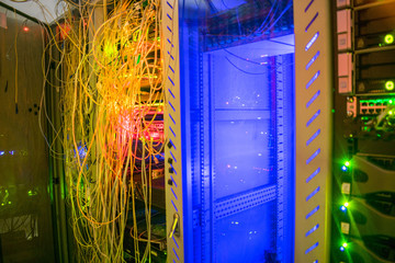 Messy wires are connected in a server rack. A lot of cables are intertwined in the computer...