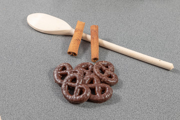 Ginger bread pretzels with chocolate beside wooden spoon and cinnamon sticks