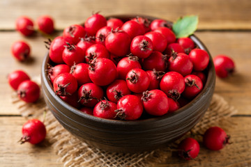Crataegus or hawthorn berries in ceramic bowl on rustic wooden background. Selective focus. - obrazy, fototapety, plakaty