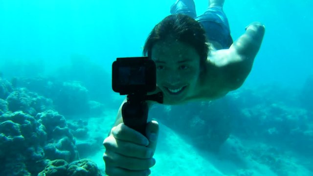 Man dives in Tahiti reef with camera, POV