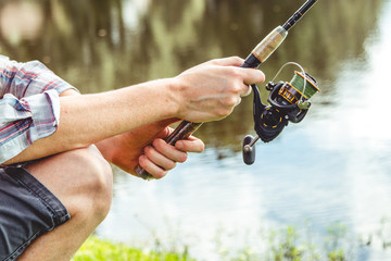 Middle age man wearing plaid shirt, fishing in lake, holding rod 