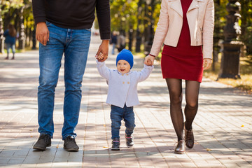 family of three for a walk. Weekend family. The first steps of the child. Parents throw baby up