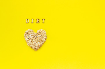 Text Diet and oat flakes in shape heart on yellow background.