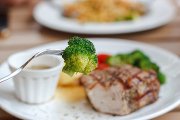 Enjoy eating bite of Broccoli with Fork and pork Juicy Steak background