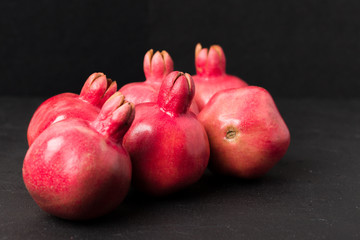Ripe red pomegranate closeup photography on black background.