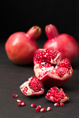 Ripe red pomegranate closeup photography on black background.
