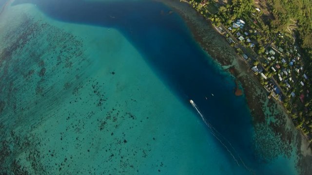 Overhead aerial, boat travels past Tahiti coast in slow motion
