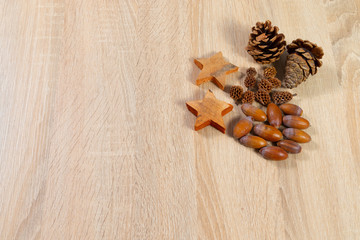 Pine cones acorns ans wooden stars with copyspace as background