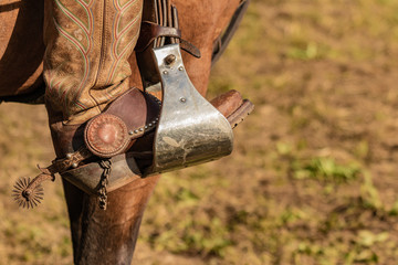 Lovely crafted stirrups and saddle, american cowboy warming up before rodeo performance on new ranch