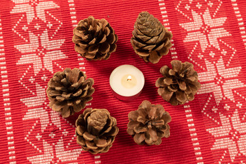 christmas decoration with candle surrounded by pine cones