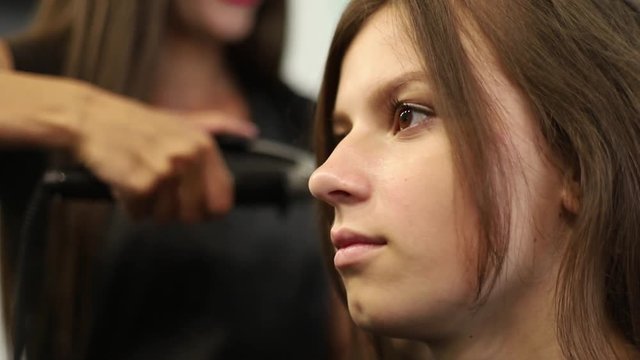 Close-up shot of a woman having her hair straightened in hair salon. Shot in slow motion. hd