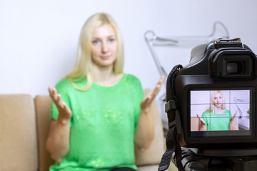 Close up photo of camera on tripod with young woman on LCD screen and blurred scene on background....