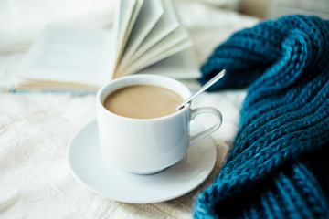 cup of tea with milk on a textile background with a knitted sweater and  needles.