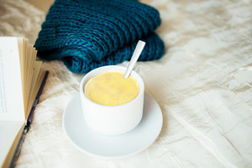 cup of tea with milk on a textile background with a knitted sweater and  needles.
