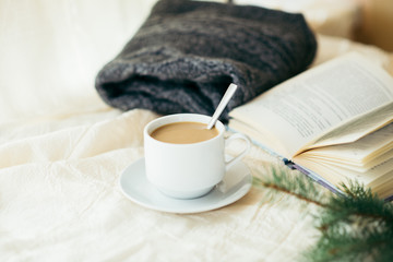 cup of tea with milk on a textile background with a knitted sweater and  needles.