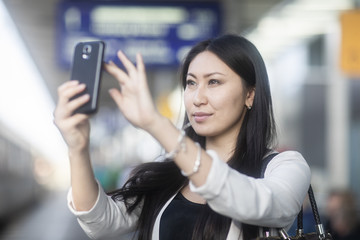 Fototapeta premium Junge Frau Asiatin kauft Ticket am Bahnhof mit Smartphone