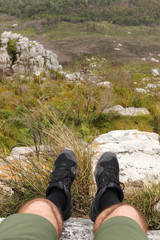 A man sitting on the edge of a cliff on Lady Slipper mountain in Port Elizabeth, South Africa. 