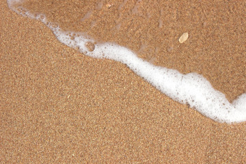 Fototapeta na wymiar Soft wave of the sea on the sandy beach background