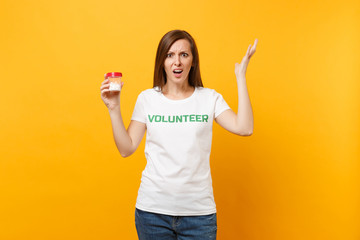 Portrait of woman in white t-shirt written inscription green title volunteer holding bottle with pills drug isolated on yellow background. Voluntary free assistance help, charity grace health concept.