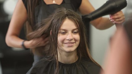 Young woman at the hair salon getting a haircut by female hairdresser