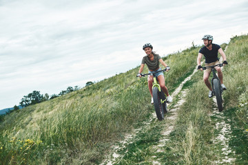 Obraz premium Young couple are cycling on fatbikes and in helmets