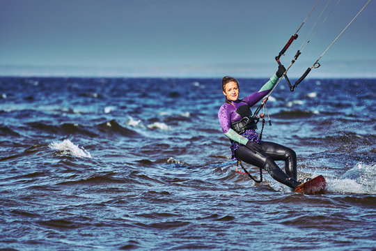 A female kiter slides on the surface of the water. Splashes of water fly apart. Close-up.