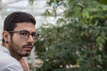 portrait of young man with glasses in a greenhouse