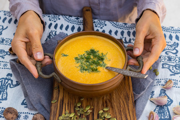 Pumpkin curry creamy soup with coconut milk, parsley. Sweet orange hot pumpkin soup in vintage pot or bowl.