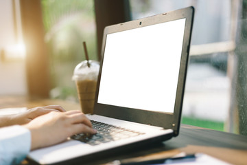 Close-up of business female working with laptop with blank white screen make a note document and smartphone in coffee shop like the background.