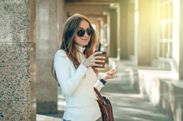 Young woman sweater sunglasses cup of coffee female bag in the street