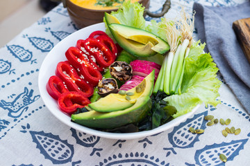 Raw vegan Buddha Bowl with avocado. Trendy healthy food style, vegetarian lunch or dinner. Balanced meal with vegetables