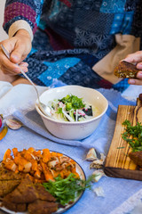 Woman hands holds okroshka - a cold soup made from cucumber, kvass, radish, dill, parsley. Vegan raw okroshka with coconut milk yoghurt, lemon, garlic. Vegetarian lunch or dinner. Healthy food.
