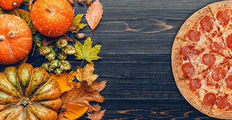 autumn background with pumpkins, autumn leaves, hops and oak acorns lying on a black wooden...