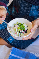Woman hands holds okroshka - a cold soup made from cucumber, kvass, radish, dill, parsley. Vegan raw okroshka with coconut milk yoghurt, lemon, garlic. Vegetarian lunch or dinner. Healthy food.