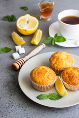 Homemade lemon muffins with honey, mint and cup of tea for breakfast on a concrete background